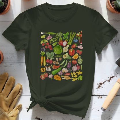 Dark green t-shirt with colorful vegetable pattern on a white wooden surface with gardening tools and plants.